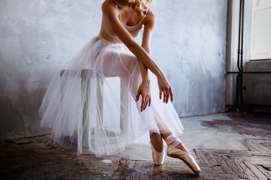 Young and slim ballet dancer is posing in a stylish studio with big windows