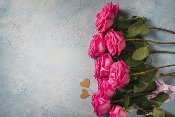 Valentines day background. Pink roses with two hearts over blue texture