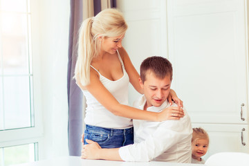 Smiling young parents and their little child are very happy at kitchen home