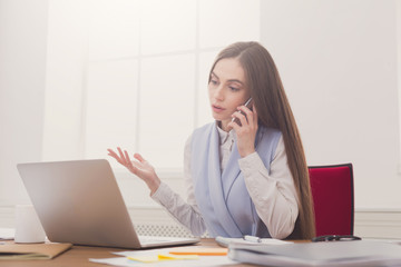 Serious business woman at work talking on phone