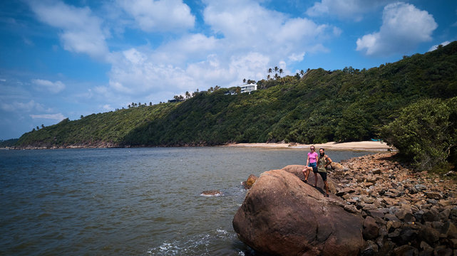 male and female standing on a stone coast