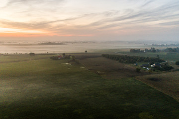 Fototapeta na wymiar Aerial view of fields with fog at amazing sunset. Summer nature landscape
