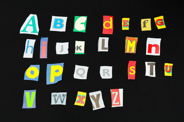 Colorful newspaper alphabet isolated on black