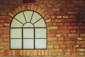 Big rounded window on red brick wall