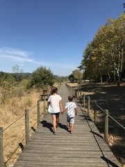 hermanos paseando en verano por las pasarelas de madera del rio 