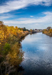River view with trees in autumn colors on both banks. A bridge is crossing the river in the...