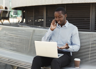 African-american businessman working with laptop outdoors