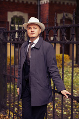 Confident middle-aged wealthy man dressed in retro style suit with white hat