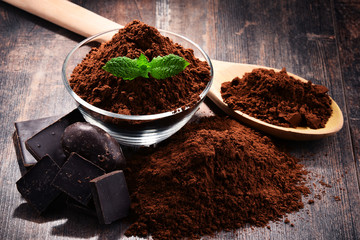 Composition with bowl of cocoa powder on wooden table