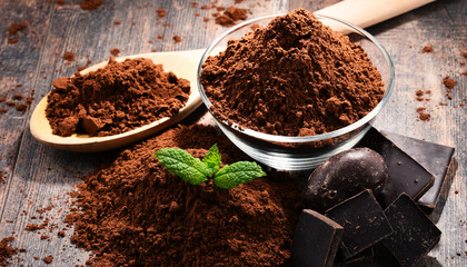Composition with bowl of cocoa powder on wooden table