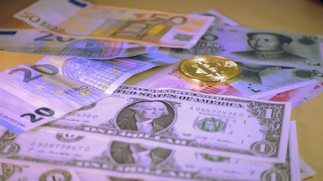 Golden bitcoin coin falling over Dollar, euro and yuan bills. Financial concept. Situation of Bitcoin and other cryptocurrencies in the real world