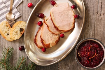 Overhead view of Sliced  roasted Turkey with cranberry sauce on wooden background