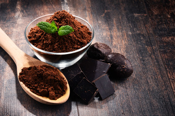 Composition with bowl of cocoa powder on wooden table