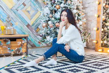 Fototapeta premium Christmas. Beautiful smiling girl. is sitting over christmas tree lights background. happy new year.