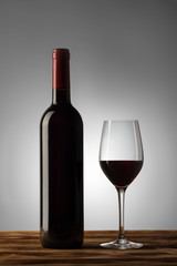 Fototapeta na wymiar Bottle and glass of red wine with a light gradient on the background