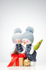 Two Snowman dolls and christmas gift box with a light gradient on the background