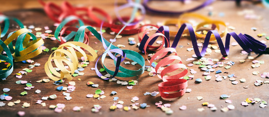 Colorful confetti and serpentines on wooden background © Rawf8