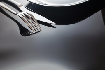 Empty plate with knife and fork on a black background