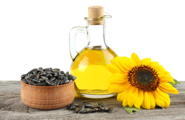 Sunflower oil in glass jug , seeds and flower on old wooden table with white background