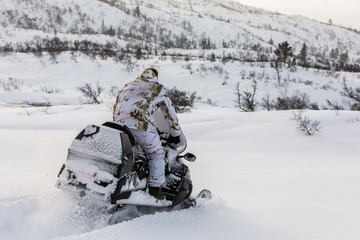 Fototapeta na wymiar Man driving snowmobile in the snow