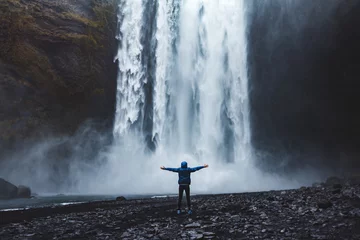 Tuinposter Een persoon die de schoonheid van de Skogafoss-waterval in IJsland bewondert © kbarzycki