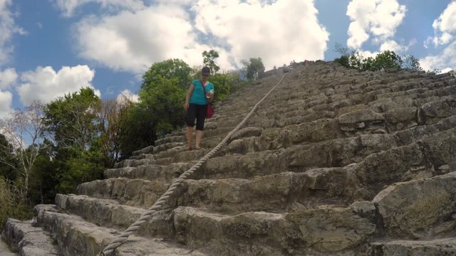 A Tourist Climbing Down Stairs On Large Mayan Ruins In Mexico