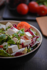 Greek salad and vegetables on the black wood table 