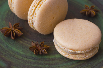 Sweet macarons and anise star on a green background.  Close-up.