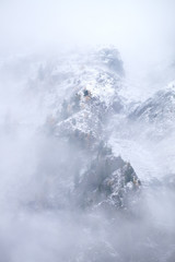 A slope of a mountain ridge with a single larch trees on it covered with a snow and hidden by the thick fog which is appeared because of frosty weather, Siberia, Altai, Shavla