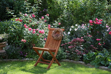 Gartenszene im Sommer mit Stuhl und Rosen in Pink