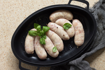 Raw homemade sausages on slate background, with basil and spices. Copy space.