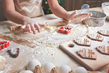 Child's hands decorate traditional Christmas cookies.