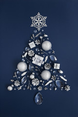 Luxury shape of New Year tree made of crystal and silver Christmas decorations on dark blue background. Holiday greeting card concept and Christmas symbol. Top view.