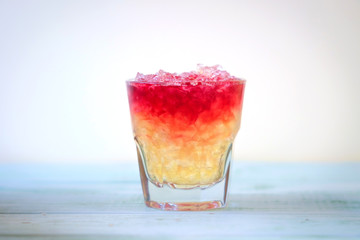 red cocktail with small ice in a glass on wooden blue background