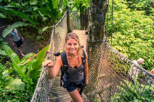 Cara&iuml;bes, Martinique, jardin de balata : femme qui traverse un pont suspendu