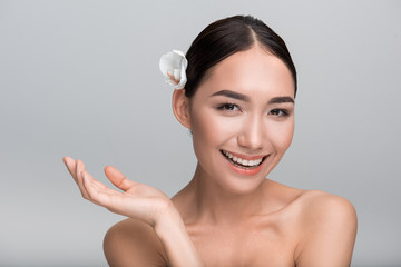 Beauty concept. Portrait of playful young gorgeous asian girl with white orchid in her hair. She is...