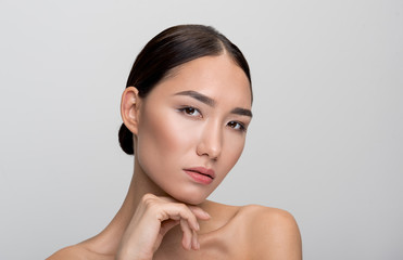Exotic beauty. Close-up portrait of elegant dark-haired young asian naked woman. She is looking at...