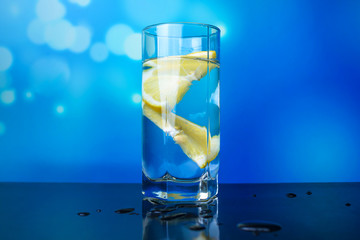A glass of water with slices of lemon on a blue background