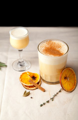 Two glasses with christmas eggnog drink decorated with cinnamon on dark background. Vertical composition.