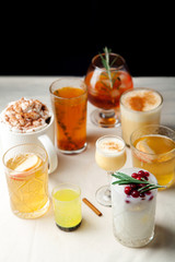 Set of various winter cocktails: mulled wine, eggnog, limoncello, old-fashioned, coconut margarita. Black background, white linen tablecloth. Vertical composition. Copy space.
