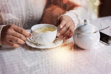 Hot cup. Beautiful white cup with tasty hot tea standing on the table next to the pretty sugar bowl while a young woman touching it with her hands