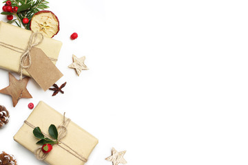 Christmas festive styled stock image composition. Handmade gift box, craft paper tag, red berries, wooden stars, dried apple and pine cones isolated on white wooden background. Flat lay, top view.