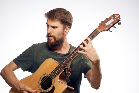 Man with a beard on a white isolated background holds a guitar, musical instruments, music