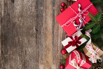 Christmas gift giving concept - christmas presents in red paper boxes with ribbons on wooden table, flat lay border with copy space