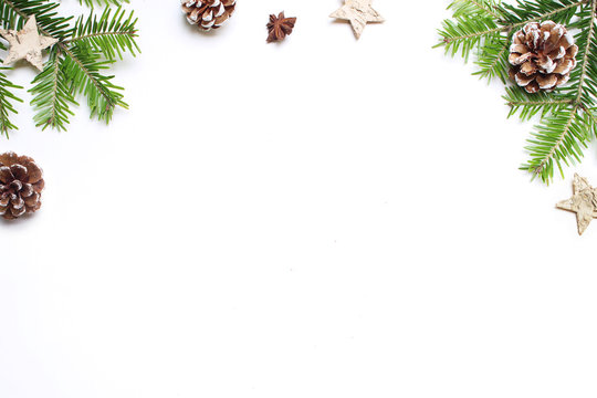 Christmas festive styled stock image. Floral frame composition with pine cones, fir tree branches, wooden and anise stars on white wooden background. Flat lay, top view with empty copy space.