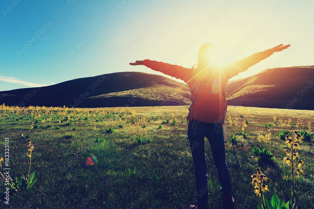 Wall mural happy woman hiker raised arms  in sunrise mountains