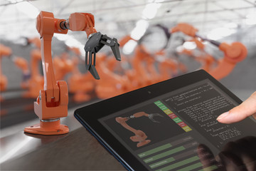 Programmer is controlling robotic arms with tablet. Automation and Industry 4.0 concept.