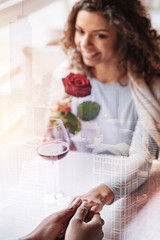 Unpredictable. Young delighted girl with curly hair and red rose looking at her man while holding his hand