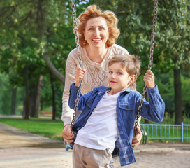 Cute little boy with grandmother in park on sunny day