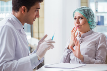 Plastic surgeon preparing for operation on woman face